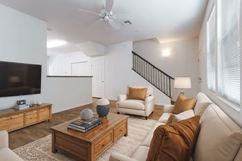 A living room with a white couch, a wooden coffee table, and a flat-screen TV.